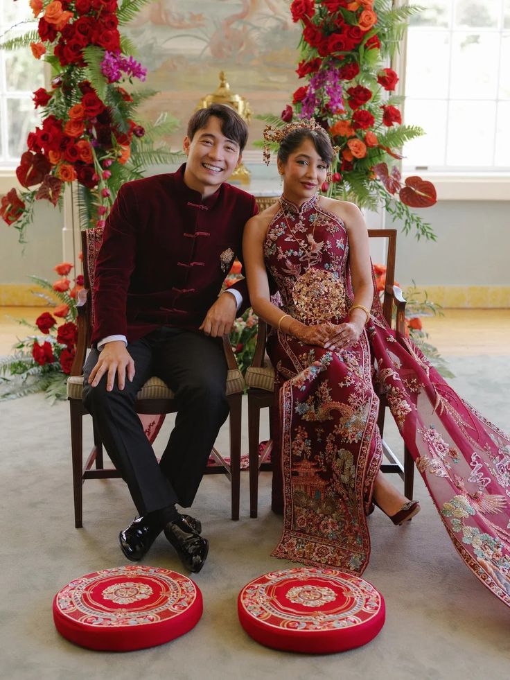 A couple in red velvet and an embroidered qipao beside a red floral arch