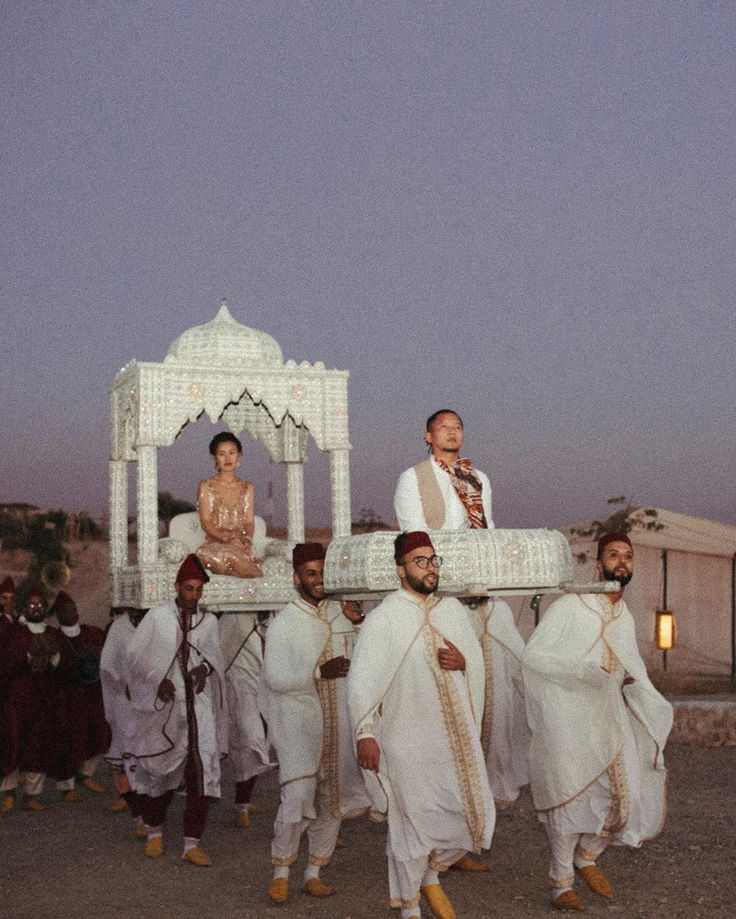 A bride and groom carried in an amariya procession at dusk