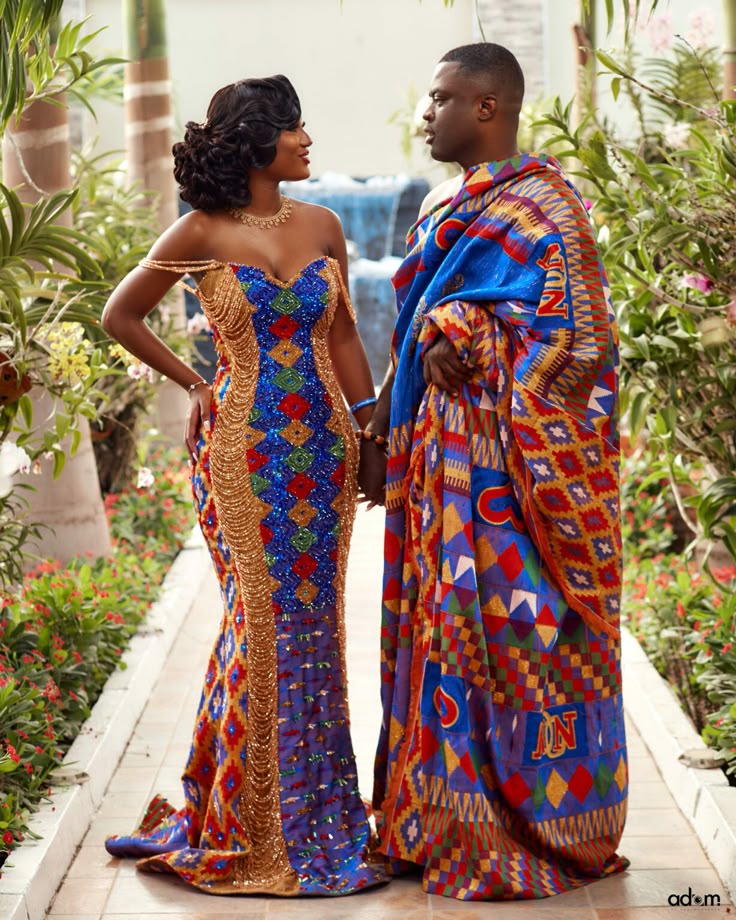 A couple in woven kente beside a garden path