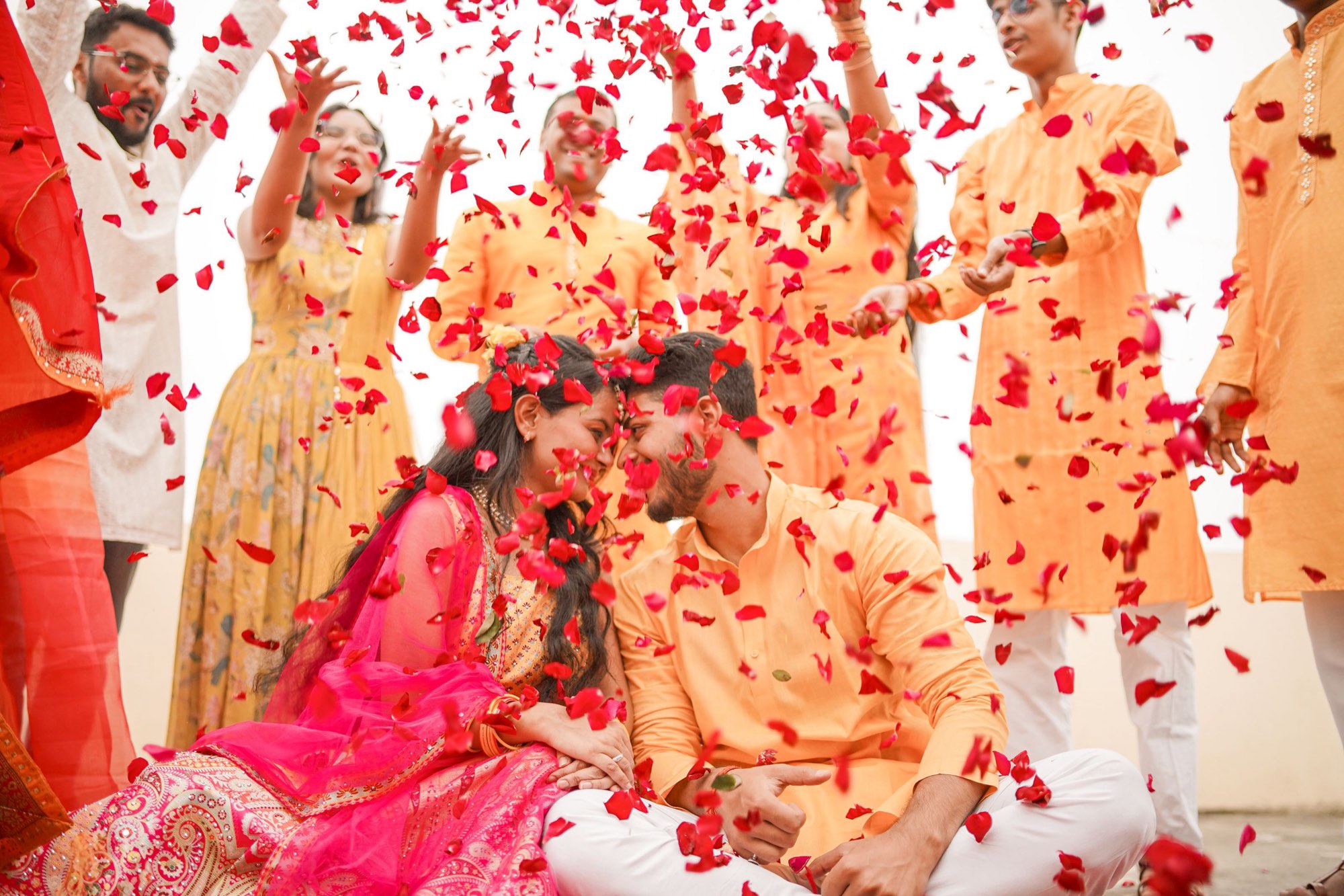 An Indian American couple at their wedding surrounded by family throwing rose petals